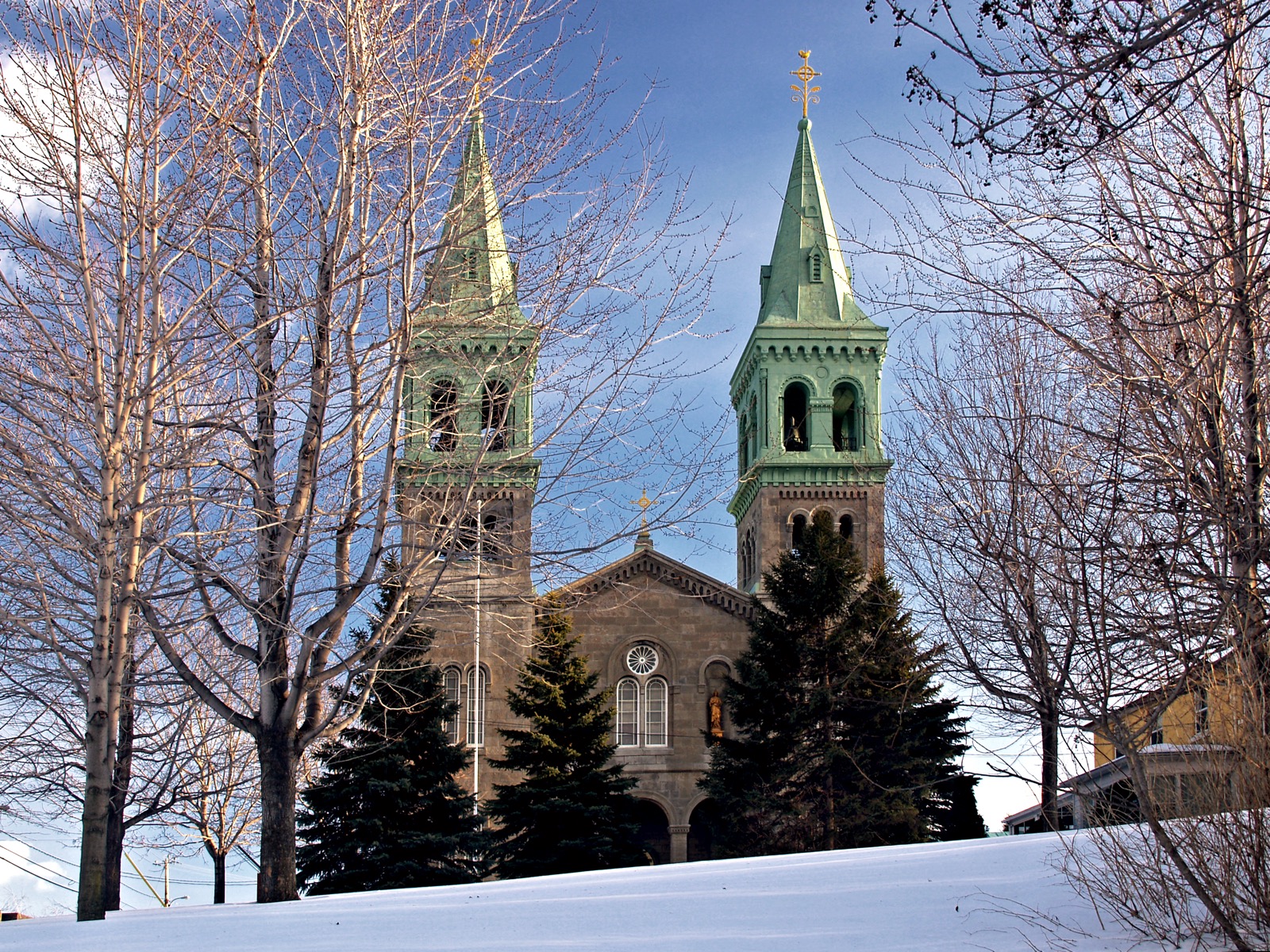 Les deux clochers verts de l'église Saint-Clément de Beauharnois entre les arbres