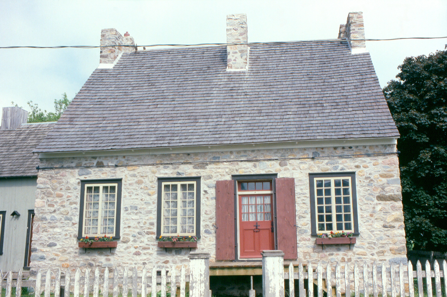 Façade en pierre de la maison Bégin et sa clôture blanche, chemin de la Beauce, à Calixa-Lavallée