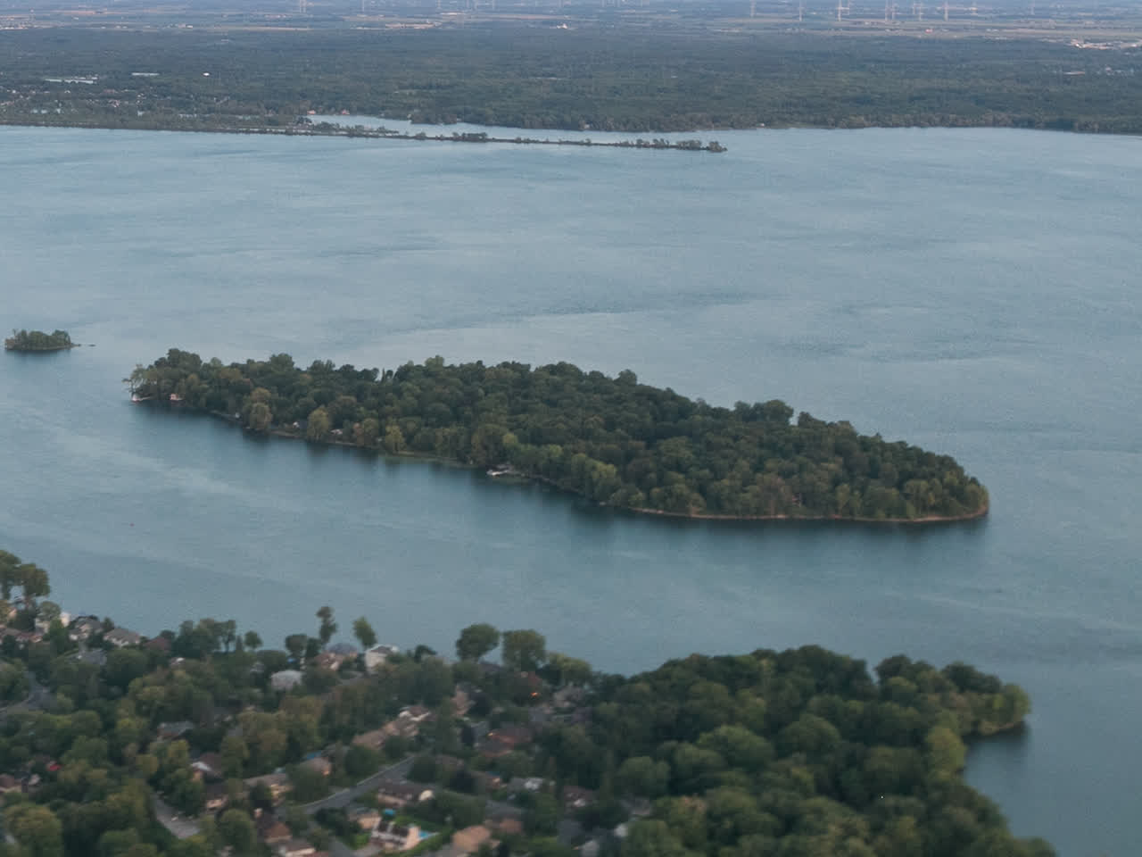 L'Île-Dorval vue du ciel, couverte d'arbres, entre la rive de Dorval et le large