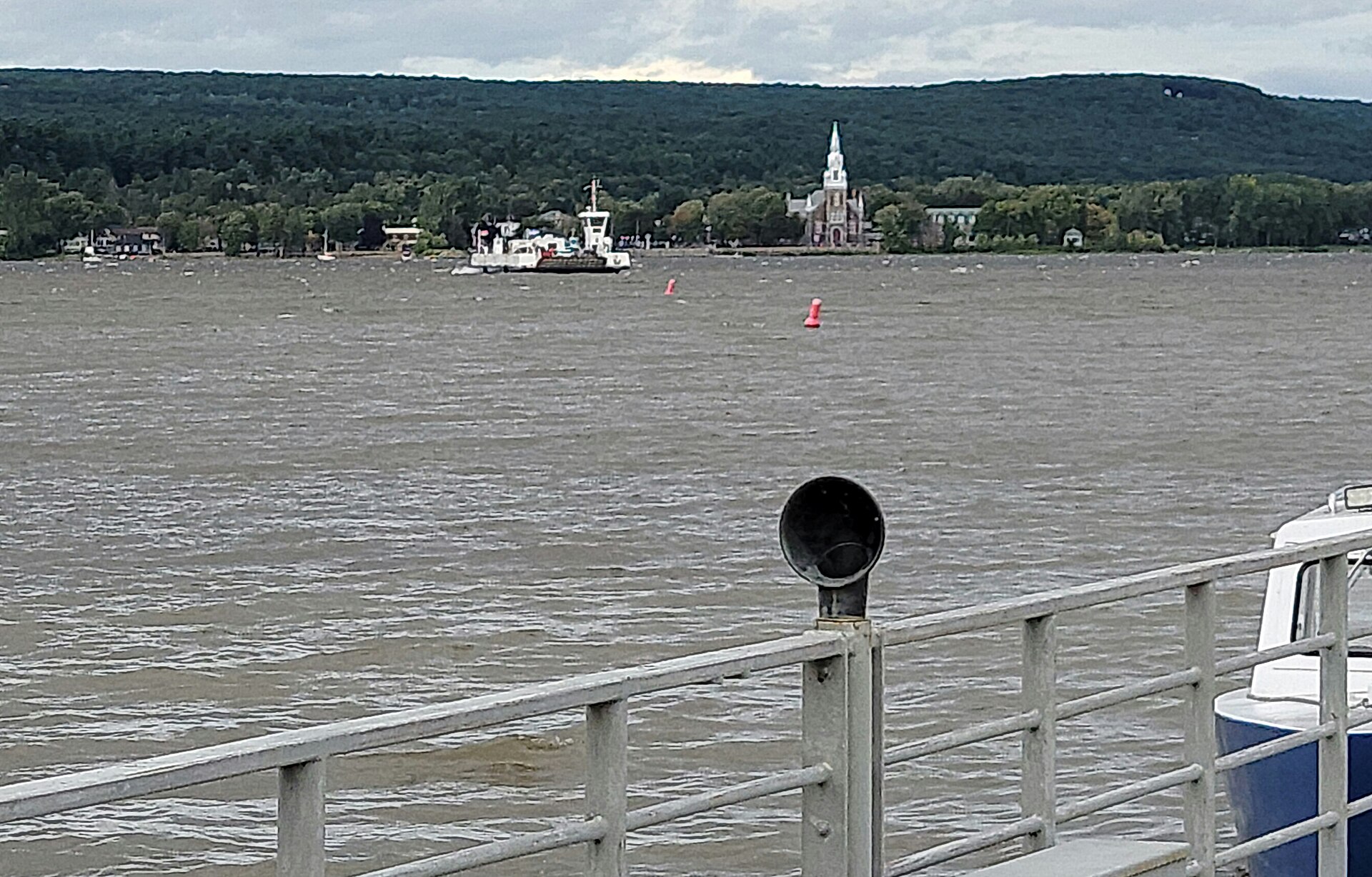 Le traversier Oka-Hudson sur le lac, avec l'église d'Oka et les collines derrière