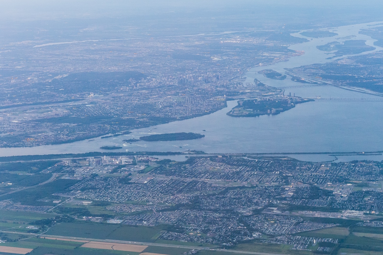 Vue aérienne de Saint-Constant et Sainte-Catherine, avec le fleuve et Montréal à l'horizon