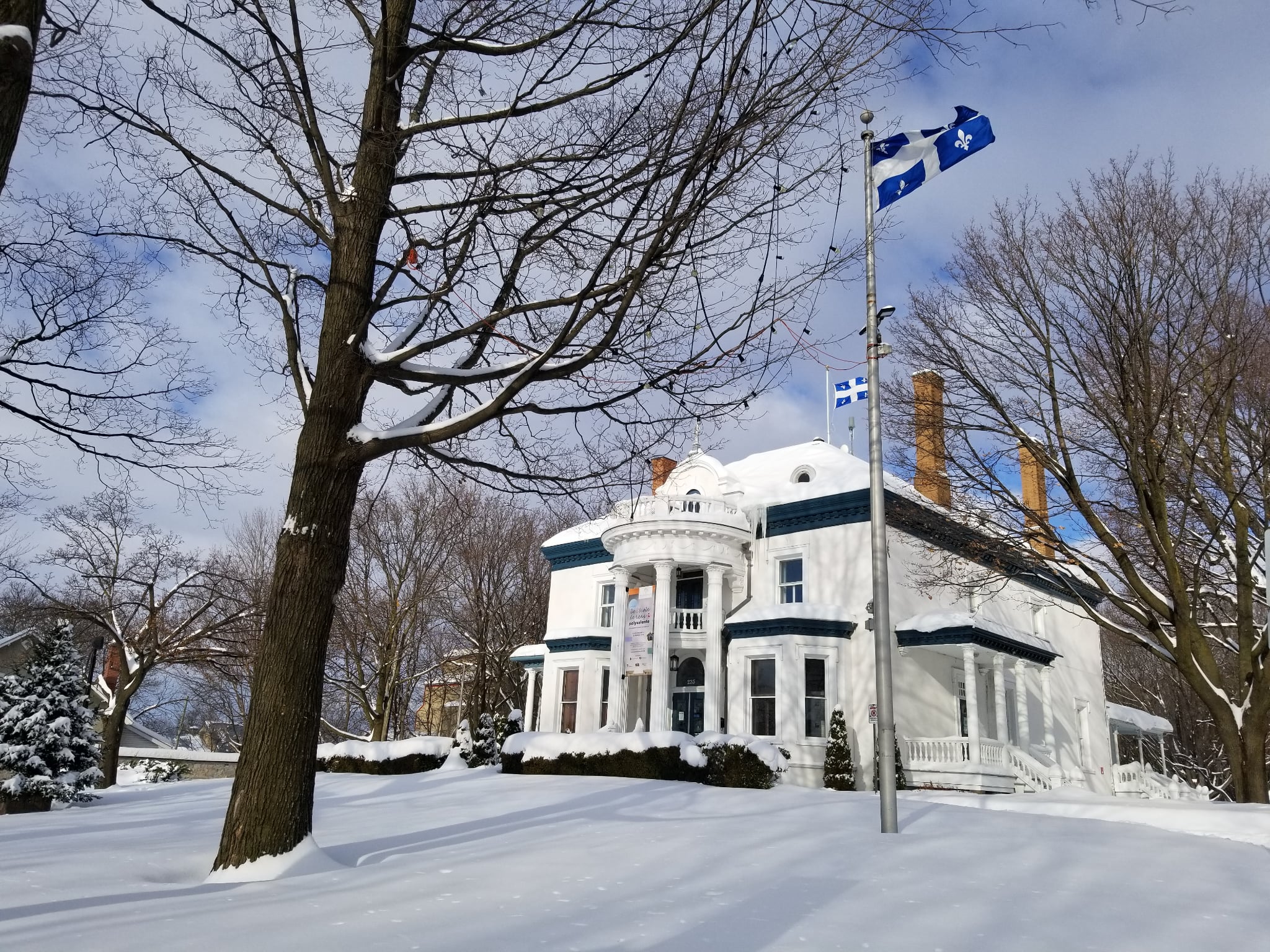 Le manoir Globensky sous la neige, avec le drapeau du Québec devant