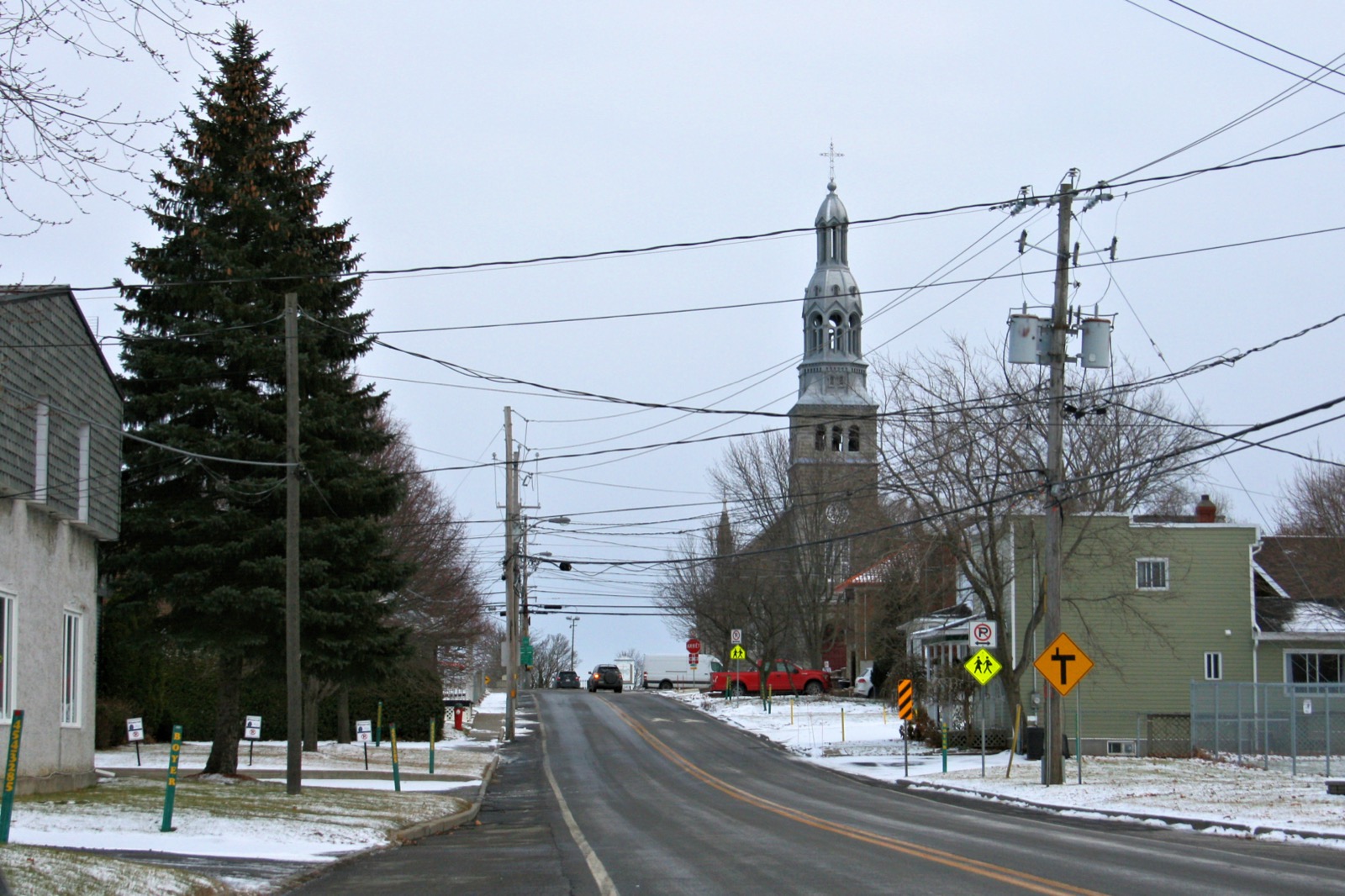 L'église de Saint-Isidore et son clocher argenté, vus depuis une rue du village en hiver