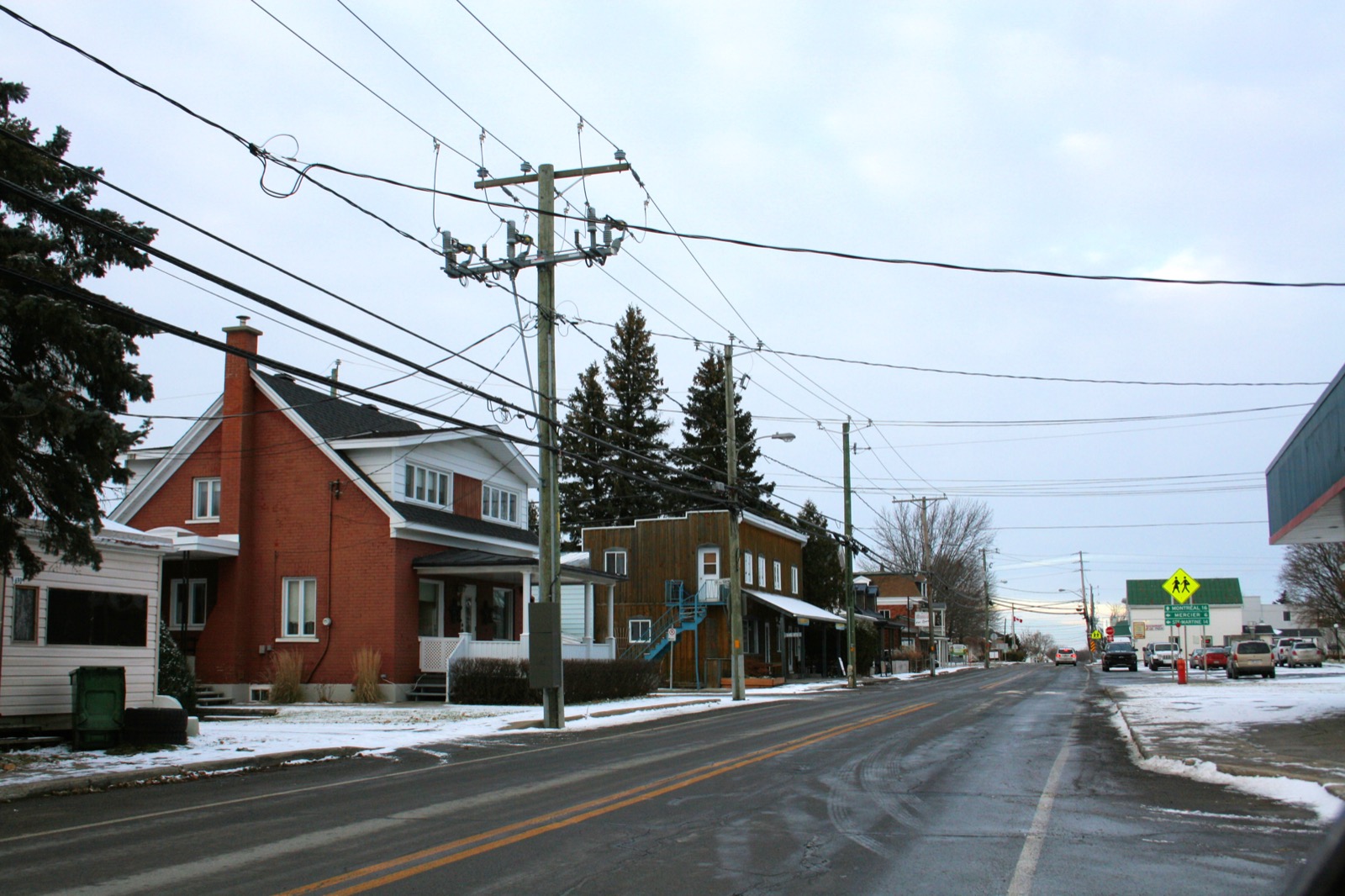 La rue Saint-Régis au cœur du village de Saint-Isidore, avec le panneau routier annonçant Montréal à 16 kilomètres